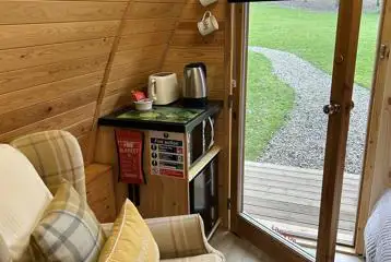 Cosy ensuite glamping pod with a kitchen corner and sofa chair
