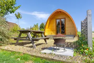 Ensuite glamping pods with a picnic bench and fire pit at Notgrove Holidays