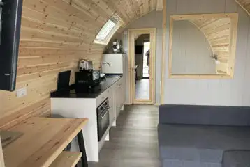Mega ensuite glamping pod interior with a sofa bed, double bed and kitchen Mega ensuite glamping pod interior with a sofa bed, double bed and kitchen