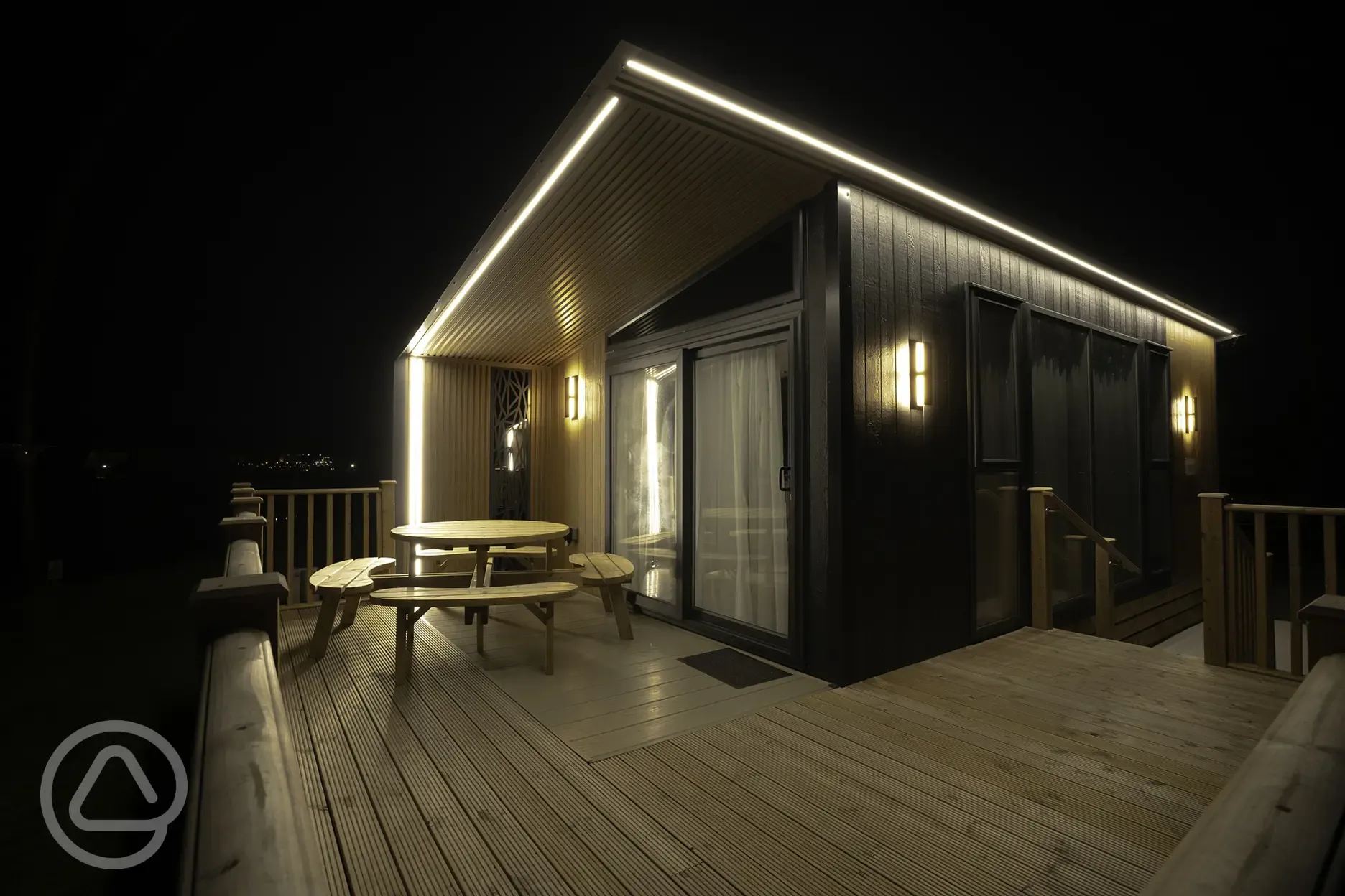 Glamping S-pod with a raised deck area at night with lighting
