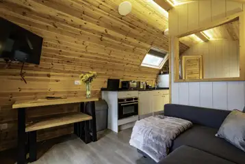 Mega glamping pod interior with a sofa bed, TV and kitchen