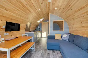 Ensuite Cosier glamping pod interior with sofa bed and TV