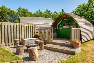 Bare Bones glamping pod with a gravel fire pit area and stool seats