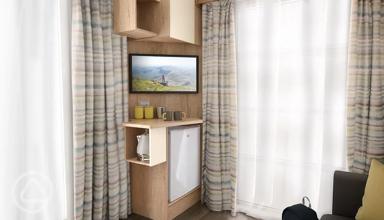 Studio pod cabin living area TV with a stored mini-fridge, kettle and crockery