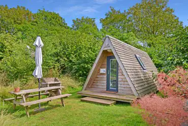 Converted chicken shed pods set amongst cob trees with outdoor seating