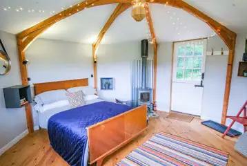Wye Glamping cabin interior with a double bed and wood burner
