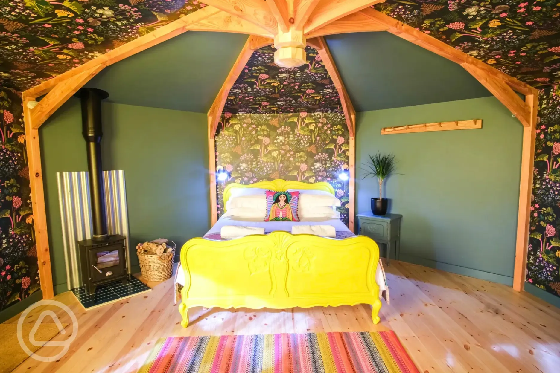 Wye Glamping cabin interior with a double bed and wood burner