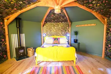 Wye Glamping cabin interior with a double bed and wood burner