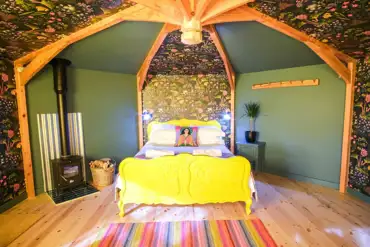 Wye Glamping cabin interior with a double bed and wood burner