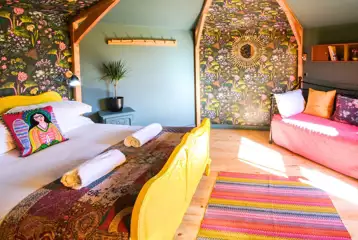 Glamping cabin interior with a double bed, two single beds and wood burner