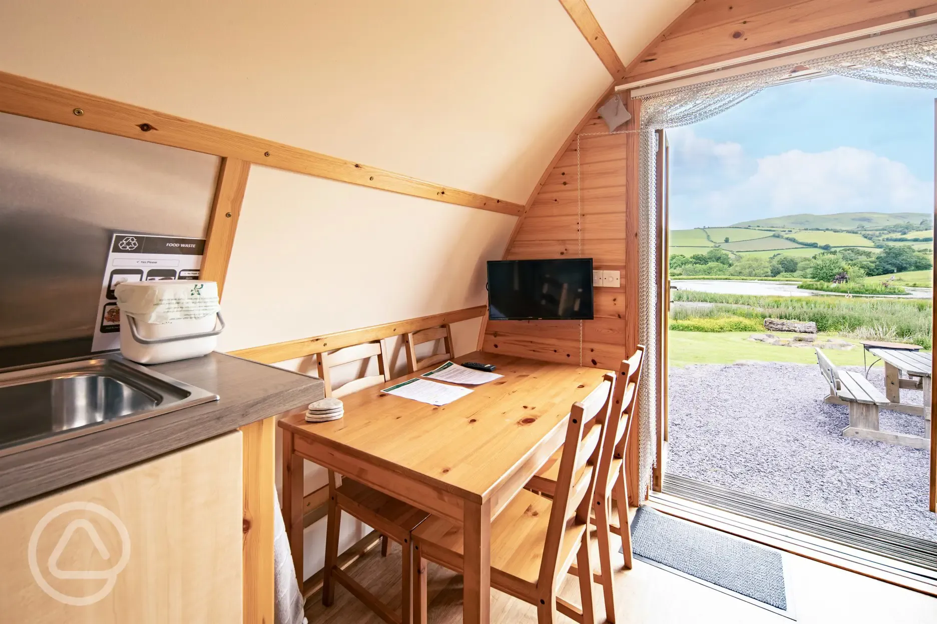 Glamping pod interior with a dining table for four and TV