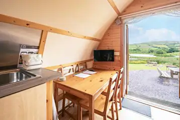 Glamping pod interior with a dining table for four and TV