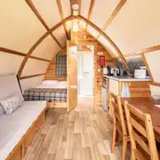 Interior of a glamping pod with a double bed, futon bed, kitchen and ensuite