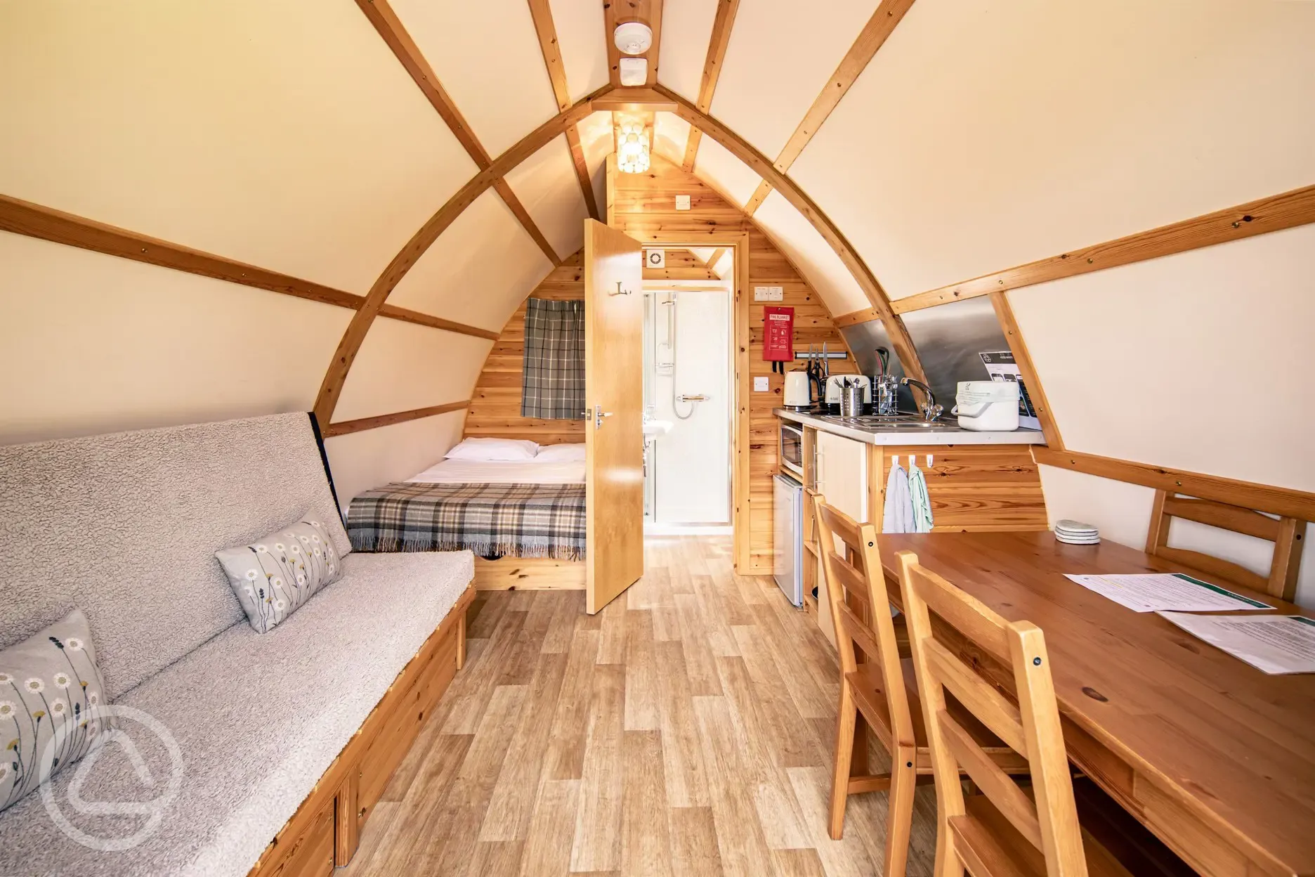 Interior of a glamping pod with a double bed, futon bed, kitchen and ensuite