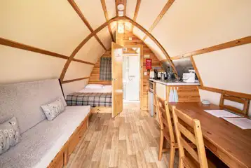 Interior of a glamping pod with a double bed, futon bed, kitchen and ensuite