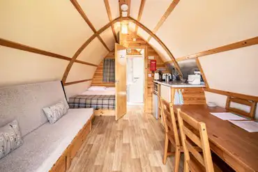 Interior of a glamping pod with a double bed, futon bed, kitchen and ensuite