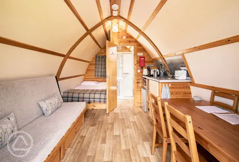 Interior of a glamping pod with a double bed, futon bed, kitchen and ensuite