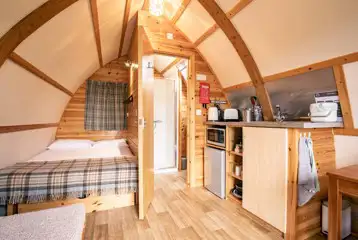 Glamping pod interior with a double bed, kitchen area and ensuite bathroom