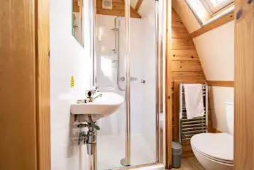Glamping pod ensuite bathroom with a toilet, shower, sink and towel rail