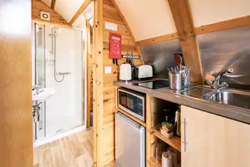 Glamping pod equipped kitchen and door to the ensuite bathroom