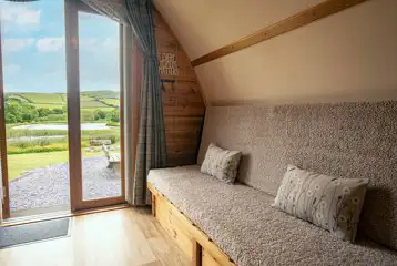 Glamping pod sofa bed with views of the lake and countryside