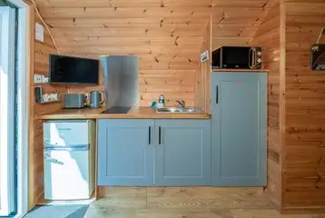 Four person pod kitchen with a fridge, microwave, sink and hob Four person pod kitchen with a fridge, microwave, sink and hob