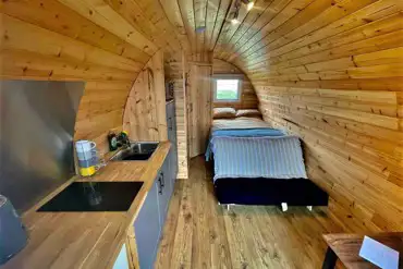 Ensuite glamping pod with a double bed and kitchenette at Pods Pwll Coch