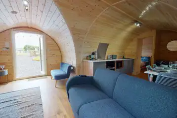 Llys Y Llwynogod pod lounge area with a sofa and kitchenette