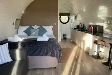 Glamping pod interior with a king size bed, kitchenette, sofa and breakfast bar Glamping pod interior with a king size bed, kitchenette, sofa and breakfast bar