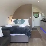Glamping pod interior with a king size bed, kitchenette, sofa and breakfast bar
