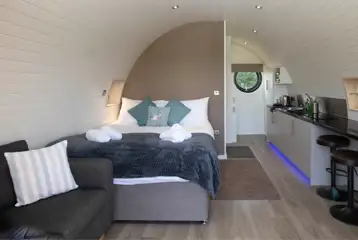 Glamping pod interior with a king size bed, kitchenette, sofa and breakfast bar Glamping pod interior with a king size bed, kitchenette, sofa and breakfast bar