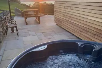 Large ensuite glamping pod hot tub and patio area at sunset Large ensuite glamping pod hot tub and patio area at sunset