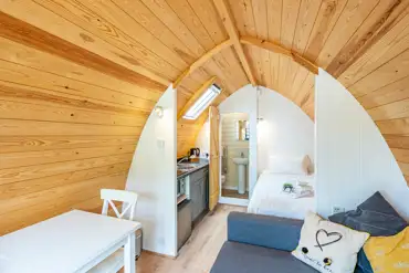 Two person glamping pod interior with bed, seating and kitchenette