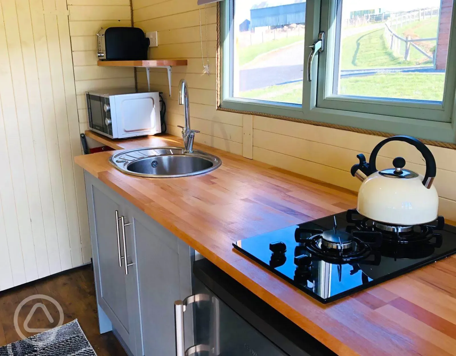 Family glamping pod kitchen area with hob, kettle, sink, microwave and toaster