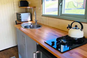 Family glamping pod kitchen area with hob, kettle, sink, microwave and toaster Family glamping pod kitchen area with hob, kettle, sink, microwave and toaster