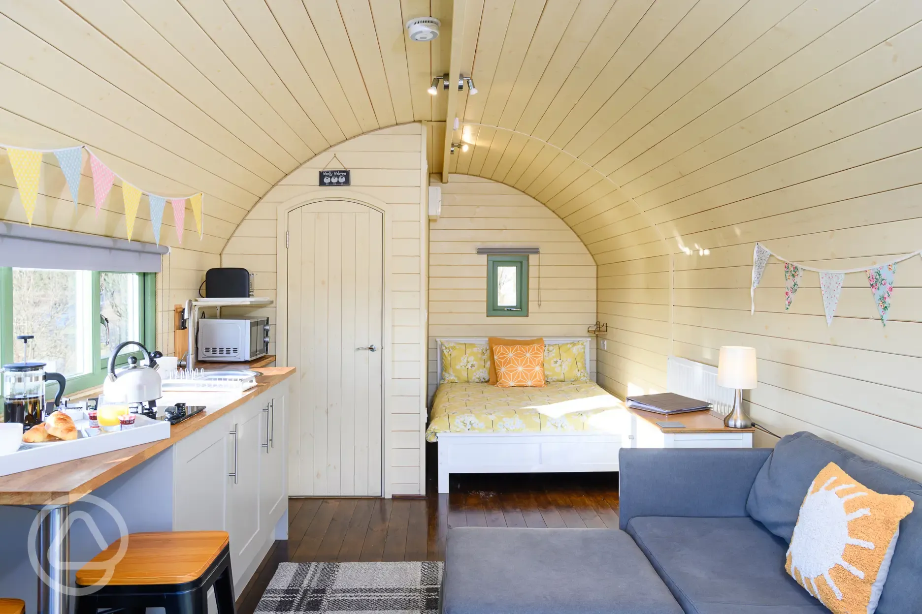 Glamping pod interior with double bed, sofa bed, ensuite, sofa and kitchenette