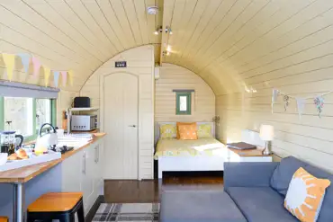 Glamping pod interior with double bed, sofa bed, ensuite, sofa and kitchenette