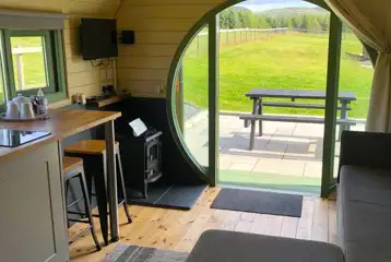 Adult only glamping pod interior with seating, log burner and countryside views Adult only glamping pod interior with seating, log burner and countryside views