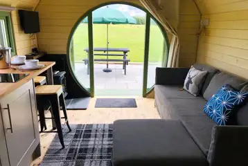 Standard glamping pod interior with sofa bed, seating and countryside views Standard glamping pod interior with sofa bed, seating and countryside views