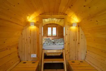 Camping pod interior with a raised bed and bench seating