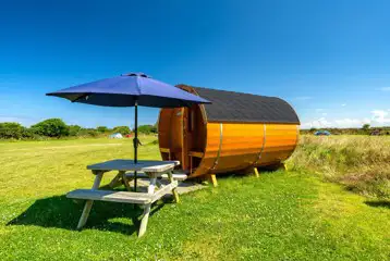 Barrel camping pod with a picnic bench and umbrella