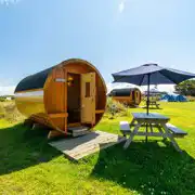 Barrel camping pod with a picnic bench and umbrella Barrel camping pod with a picnic bench and umbrella