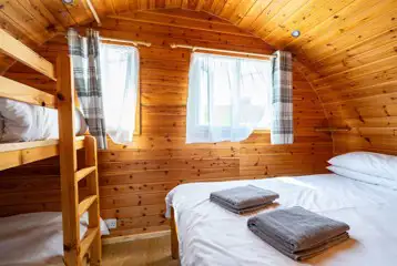 Glamping pod bedroom with a double bed and bunk beds