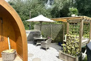 Willow glamping pod with a pergola seating area, table, chairs and hot tub