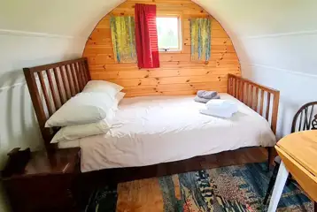 Camping pod interior with a double bed and bedding