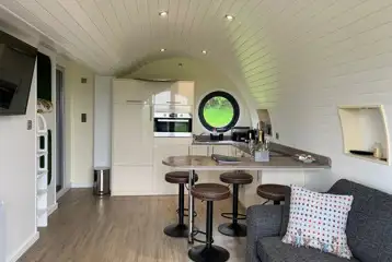 Wye glamping pod interior with a kitchen, sofa and breakfast bar Wye glamping pod interior with a kitchen, sofa and breakfast bar