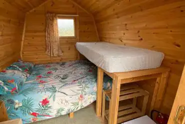 Log pod interior with double bed and bunk bed