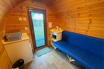 Camping pod interior with a with a kettle, microwave, and mini fridge