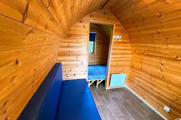 Camping pod interior with a small double and padded bench seating/bed 