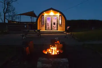 Glamping pods at night with fire pits Glamping pods at night with fire pits